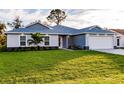 Beautiful single Gathering home showcasing a well-manicured lawn, lovely landscaping, and a two-car garage at 27260 Porto Nacional Dr, Punta Gorda, FL 33983