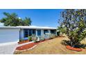 Inviting home showcases well-manicured landscaping, a vibrant blue door and tasteful gray and blue trim at 458 Azalea Nw Ave, Port Charlotte, FL 33952