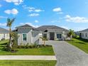 Stunning single-story home features a gray tile roof, manicured lawn, and a paved driveway leading to the front door at 17336 Sandpearl Rd, Venice, FL 34293