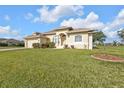 Inviting single-story home with a well-manicured lawn and colorful garden beds at 235 Tournament Rd, Rotonda West, FL 33947
