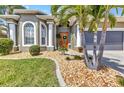 A covered front entry and beautiful landscaping lead to a decorative glass front door and welcoming entrance at 24260 Westgate Blvd, Port Charlotte, FL 33980