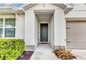 Inviting front entrance featuring a covered porch with a modern gray door and manicured bushes at 25340 E Lenox Cir, Punta Gorda, FL 33950