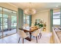 Elegant dining room with modern chandelier, neutral decor, and sliding glass doors to a screened patio at 264 Soliera St, Nokomis, FL 34275