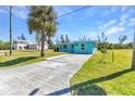 Quaint blue home with a long driveway, a well-maintained lawn and mature palm trees at 312 Darst Ave, Punta Gorda, FL 33950