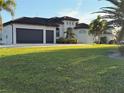 Lawn view of an exterior of a one story home featuring a tile roof, palm trees and a two-car garage at 3414 Sandpiper Dr, Punta Gorda, FL 33950