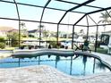Screened in pool area with in ground pool, brick patio, and view of boats on the canal at 3414 Sandpiper Dr, Punta Gorda, FL 33950