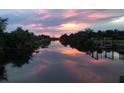 Serene water view reflecting a colorful sunset, surrounded by lush greenery and dock structures at 4053 Joseph St, Port Charlotte, FL 33948