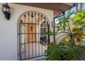 Inviting front entry with an arched gate, textured stucco, and tropical plants enhancing the home's curb appeal at 4438 Meager Cir, Port Charlotte, FL 33948
