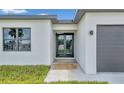 Modern home featuring a glass front door and manicured front lawn at 551 Crandall Nw St, Port Charlotte, FL 33952