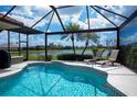 Relaxing screened-in pool area with lounge chairs, overlooking a serene lake and picturesque scenery at 5733 White Jasmine Way, North Port, FL 34287