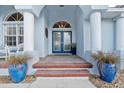 Close up of the inviting brick-lined entryway with double doors, decorative columns, and potted plants at 1091 Rotonda Cir, Rotonda West, FL 33947