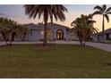 Inviting single-Gathering home featuring a beautifully landscaped front yard and a charming blue exterior with palm trees at 1091 Rotonda Cir, Rotonda West, FL 33947