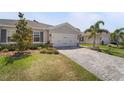 Attractive one-story home with a well-manicured lawn, a paved driveway, and a two-car garage at 1796 W Palms Dr, Port Charlotte, FL 33953