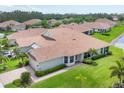 Areal view of a single-story home with a tiled roof, well-manicured lawn, and a pond view at 1940 Scarlett Ave, North Port, FL 34289
