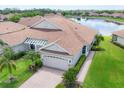 Beautiful single-story home with a lake view, tiled roof, paved driveway, and an attached two-car garage at 1940 Scarlett Ave, North Port, FL 34289
