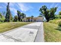 Spacious driveway leads to a charming single-story home with a well-kept lawn, mature trees, and a one-car garage at 2679 Pascal Ave, North Port, FL 34286