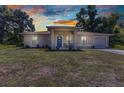 Charming single-story home with a blue front door, and well-maintained lawn under a sunset sky and mature trees at 2679 Pascal Ave, North Port, FL 34286