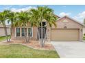 Charming home featuring a well-manicured lawn, mature palm trees, and a two-car garage at 2699 Suncoast Lakes Blvd, Punta Gorda, FL 33980