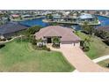 Beautiful home with lush landscaping on the canal, a paver driveway, and a three-car garage at 2850 Magdalina Dr, Punta Gorda, FL 33950