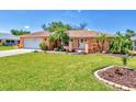 Charming single-story home featuring a manicured lawn and lush tropical landscaping at 3287 Meadow Run Cir, Venice, FL 34293