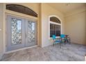 Close-up of the tiled front porch with seating area, decorative windows, and double door entry at 3614 January Ave, North Port, FL 34288
