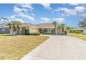 Inviting one-story home with a long driveway, well-manicured lawn, and lush tropical landscaping with palm trees at 18379 Edgewater Dr, Port Charlotte, FL 33948
