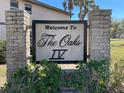 Welcome to The Oaks IV community sign, surrounded by greenery and stone pillars at 19505 Quesada Ave # Ee202, Port Charlotte, FL 33948