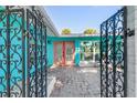 Inviting entrance featuring a decorative gate, brick pavers, and vibrant coral doors at 1960 W Marion Ave, Punta Gorda, FL 33950