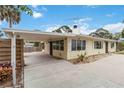 Exterior view of the home showcasing its light yellow siding, carport, and well-maintained landscaping at 217 Palm E Ave, Nokomis, FL 34275