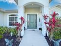 Close up of the front door with decorative plants and charming accents at 25428 Islas Dr, Punta Gorda, FL 33955