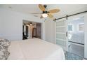 Open bedroom with sliding barn door, ceiling fan, and ensuite bathroom at 4238 Gardner Dr, Port Charlotte, FL 33952