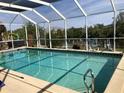 Sparkling screened-in pool with clear blue water and a view of the lush backyard and canal at 4238 Gardner Dr, Port Charlotte, FL 33952
