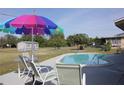 Inviting backyard oasis features a private in-ground pool and a colorful umbrella over the seating area at 474 Elm Nw Ave, Port Charlotte, FL 33952