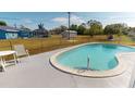 Backyard showcasing a refreshing in-ground pool with surrounding concrete patio and a secure chain-link fence at 474 Elm Nw Ave, Port Charlotte, FL 33952