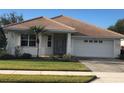 Inviting single-story home featuring a tiled roof, a front-facing garage, and an easy-to-maintain lawn at 6379 Grand Cypress Blvd, North Port, FL 34287