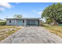 Single story home featuring a wide driveway, mature landscaping, and a covered carport entryway at 103 Curtis Ne Ter, Port Charlotte, FL 33952
