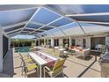 Inviting screened-in patio featuring a pool, dining area, lounge chairs and outdoor kitchen at 4146 Library St, Port Charlotte, FL 33948