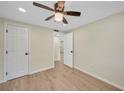 Bright bedroom featuring a ceiling fan, wood-look flooring, and a hallway leading to other rooms at 654 Aqui Esta Dr, Punta Gorda, FL 33950