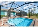 Inviting screened-in pool area featuring a pristine pool, lounge chairs, and a view of the surrounding greenery at 8117 Thruso Rd, Port Charlotte, FL 33981