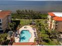 Aerial view of community pool and spa with tropical landscaping and views of the water at 95 N Marion Ct # 126, Punta Gorda, FL 33950