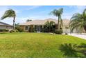 Inviting single-story home with a spacious lawn, decorative palms, and well-maintained landscaping at 1240 Alpinia Rd, North Port, FL 34288