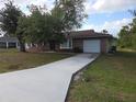 Charming brick home with an attached garage and a long driveway leading to the residence at 18054 Ackerman Ave, Port Charlotte, FL 33948