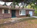 Well-maintained brick home featuring a bay window, screened front door and attached single car garage at 18054 Ackerman Ave, Port Charlotte, FL 33948