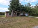 Quaint brick home with mature trees, a bay window, and an attached single-car garage at 18054 Ackerman Ave, Port Charlotte, FL 33948