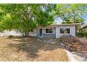 Modest one-story home exterior with tree cover and muted gray brick facade near entryway at 2677 Martin St, Sarasota, FL 34237