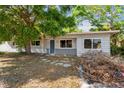Modest one-story home exterior with tree cover and muted gray brick facade near entryway at 2677 Martin St, Sarasota, FL 34237
