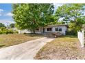 Modest one-story home exterior with tree cover and muted gray brick facade near entryway at 2677 Martin St, Sarasota, FL 34237