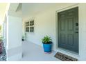 Inviting front entry with a gray door, modern door hardware, potted plants, a welcome mat, and sidelight window at 2903 Pope St, North Port, FL 34287
