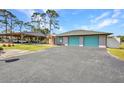 Spacious garage with teal doors and adjacent carport, providing ample parking and storage space for vehicles and equipment at 29324 Leah Rd, Punta Gorda, FL 33982