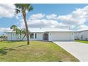 Charming home with a metal roof, lush lawn, mature palm trees, and a convenient two-car garage at 5194 Cooper Ter, Port Charlotte, FL 33981